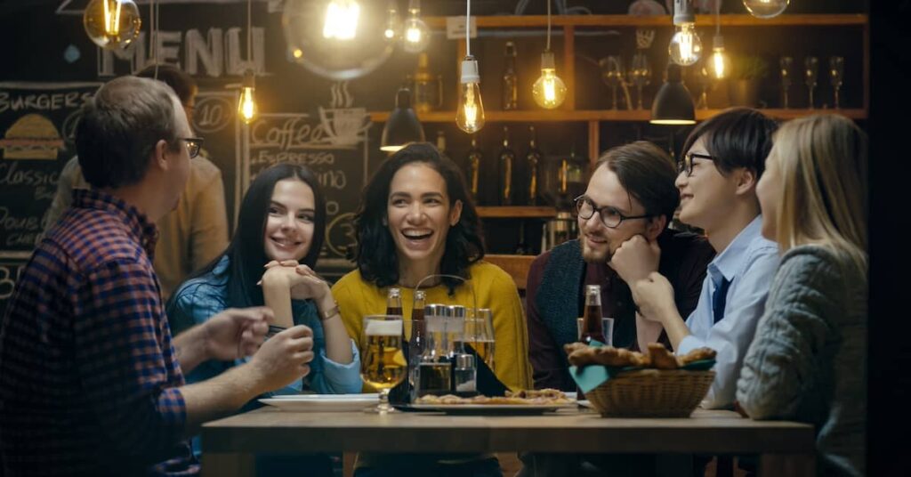 Group of friends happily eating together at a trendy restaurant | Twelve Three Media